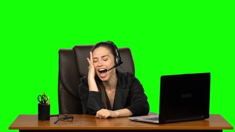 Business girl in headphones speaking by webcam and look at laptop with emotions of joy. Green screen