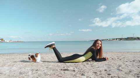 Young adult athlete woman playing with little pet on beach
