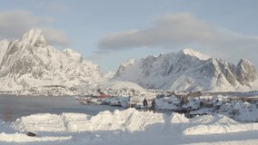 Aerial drone video of the snowy mountains in Reine village during winter at the Lofoten Islands of Norway.