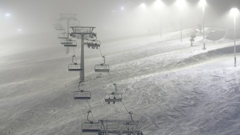  Dreamy view of a lofty ski-lift without sitting skiers going up in Levi ski resort in Finland in winter. Two rows of lit lamposts are placed along it. Stock Video
