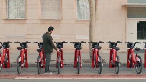 Tourist man take Electric Kick scooter or bike bicycle in sharing parking lot, tourist phone application. New sharing business project started in city, eco transportation