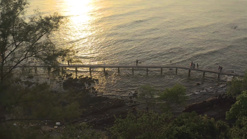 Aerial view of people enjoying nature at sunrise and walking over wooden platform