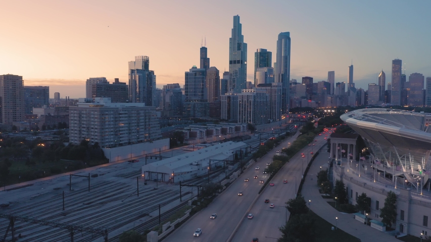 Aerial: Rush hour traffic, train tracks and Chicago skyline at night. USA 