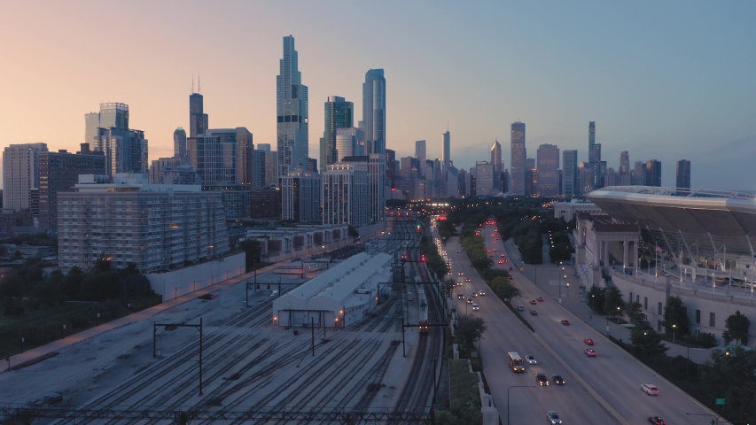 Aerial: Rush hour traffic, train tracks and Chicago skyline at night. USA 