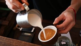 Cropped shot of Barista hand trying to pouring steamed milk to hot coffee to making latte art. A latte is a coffee drink made with espresso and steamed milk.