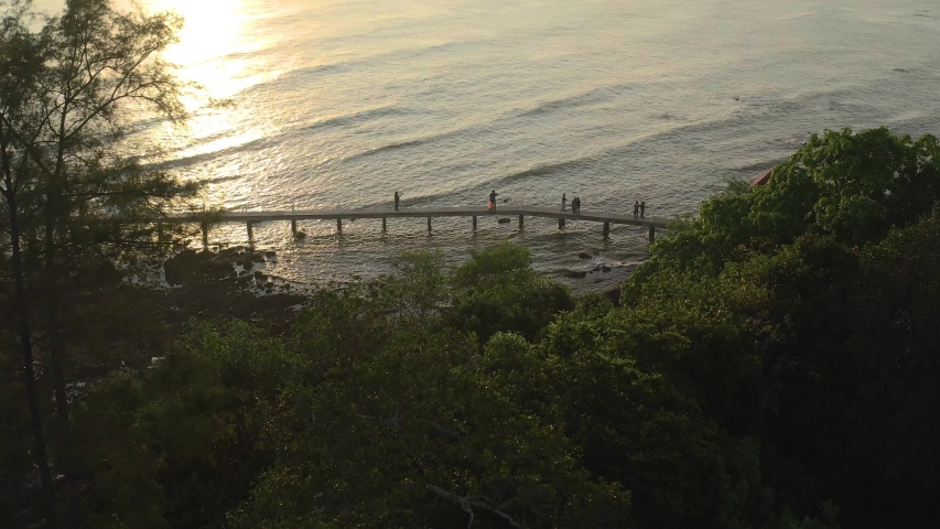 Aerial view of people enjoying nature at sunrise and walking over wooden platform