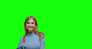 Young cheerful woman pointing to side and upwards with both hands showing object in copy space against green screen background . Girl having fun on Chroma Key. 4k video footage slow motion 60 fps