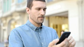 Serious adult man walking in the street using smart phone