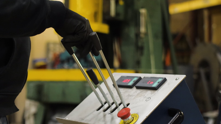 gloved hand pulling levers on heavy machinery in factory	