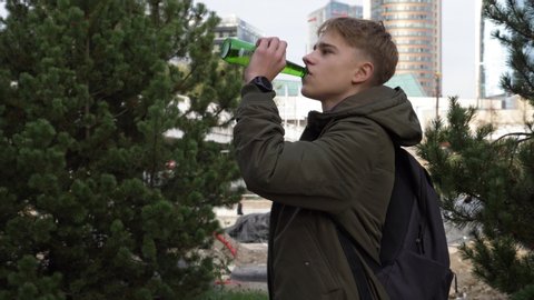 Teenager secretly drinking alcohol in the city center and watching if nobody is coming