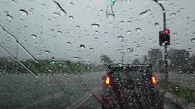 Clips video of Rain falling on car windshield, drive car on street in city at heavy rain. 30 frame rate per seconds