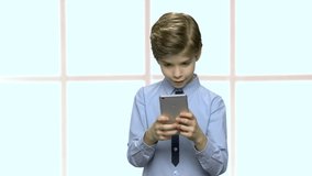 Handsome little boy using smartphone. Kid browsing internet on mobile phone. Harmful effects of technology on children.