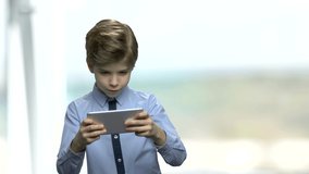 Preteen boy playing game on smartphone. Excited child playing video game on phone against blurred background. Youth, technology, lifestyle.