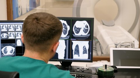 Radiologist looking at monitors with lungs activity results in control room. 4K