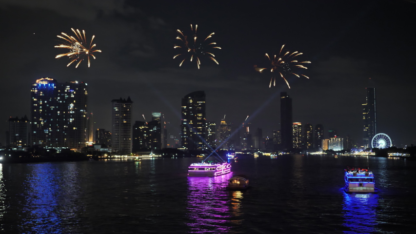 Fireworks over Bangkok city Riverside chao phraya with hotels building and service boats for celebrating New year