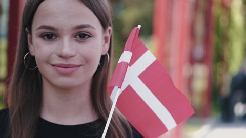 A student is showing the Danish flag. The flag is waving on a stick.