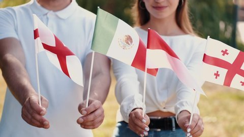 European students are waving the flags of countries. There are English, Mexican, Polish and Georgian flags.