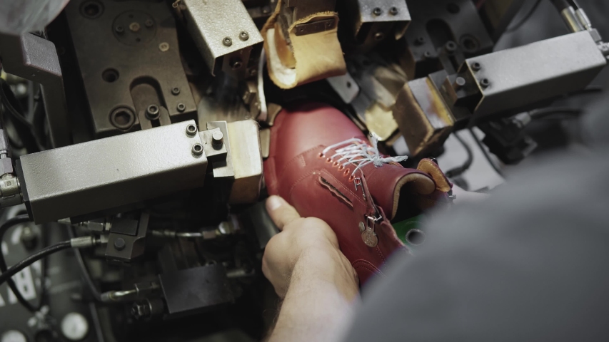 Man use special machine tool for making a shoes. The conveyor on a shoes factory with shoe and sole. Mass production of footwear.