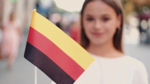 A student is waving German flag on a stick. The girl is on the street.