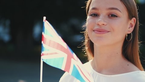 European student is waving the flag of Great Britain. The girl is smiling.