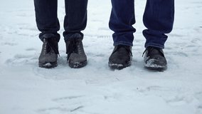 Feet of a man and a woman wearing shoes freezing from the cold and shifting from foot to foot on the snow in winter. People dancing trying to warm. 4K resolution video.