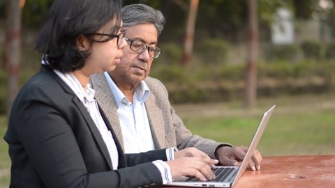 Lifestyle shot - Digital India
Young Indian woman manager/entrepreneur in a black blazer teaching her retired father, old Indian man on a laptop promoting digital literacy for elderly in a park, India