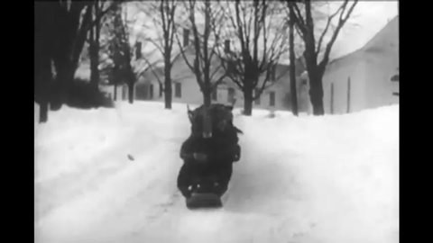 CIRCA 1940 - The record-holding longest bobsled hauls a pack of children into town.