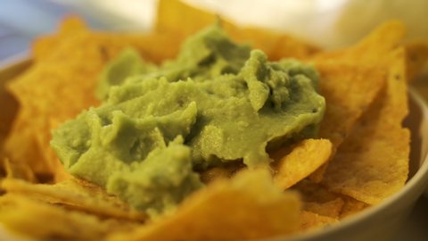 Macro view of a person eating guacamole while scooping a chip