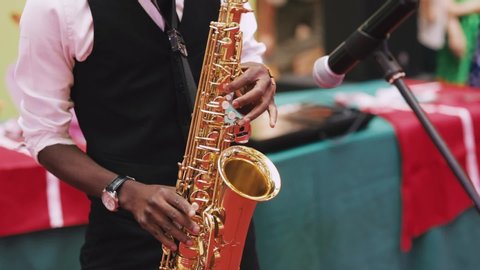Afro american Musician playing saxophone on european city sidewalk close up