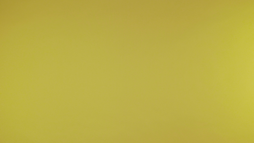female hands neatly hold a small paper heart on an isolated yellow background. 4K