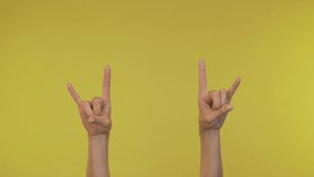Woman hands showing rock gestures over yellow background 4K