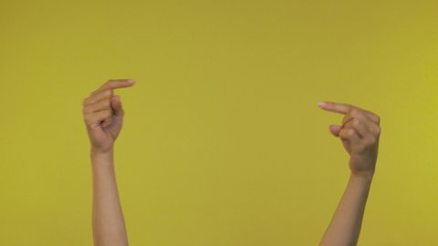 Female hands over a yellow background pointing at something. Close up footage of hand only 4K