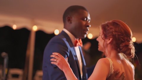 An awkward bride and groom dance at their tent canopy wedding reception