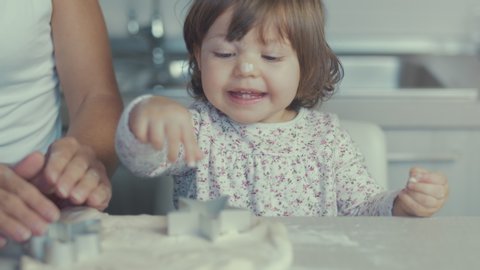 Closeup of young mother and little cute daughter cooking together preparing cookies and pizza with biscuit cutter and a dough in the kitchen. Close up on hands. Shot in 6k, cine lens. Instagram style.