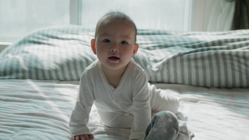 Slow motion of lovely asian baby playing at home in bedroom looking at camera smile 9 months happy baby playing Lovely baby girl crawling in bed Chinese baby girl portrait Royalty-Free Stock Footage #1044255088