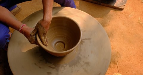 Skilled wet hands of potter shaping the clay on potter wheel and sculpting vase. Manufacturing traditional handmade Indian bowl, jar, pot, jug. Shilpgram, Udaipur, Rajasthan, India