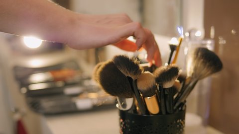 Professional make-up brushes in tube. Make-up set. Beauty salon. Professional makeup artist selects the right makeup brush from a set, close-up.