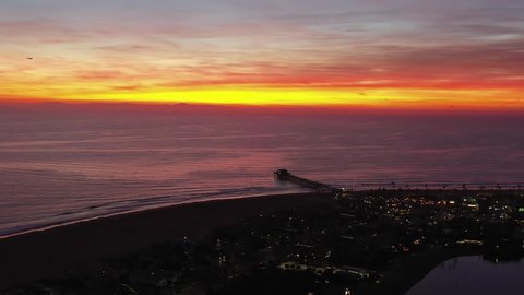 Aerial view or drone shot of beautiful pink sunset with horizon over Newport Beach, Orange County pier in California during twilight.