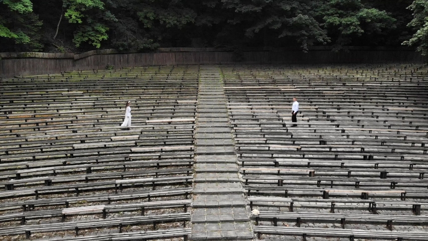 Aerial view Two young men in an abandoned Park approach each other and hold hands. An abandoned Park with wooden benches.