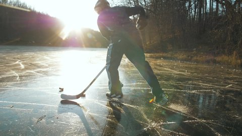MOSCOW, RUSSIA, 10 DECEMBER 2019: Hockey player on frozen lake make ice sparkles on high speed braking.hockey stick in hands, canadian tricks, young man outdoor training in canada Toimituksellinen arkistovideo