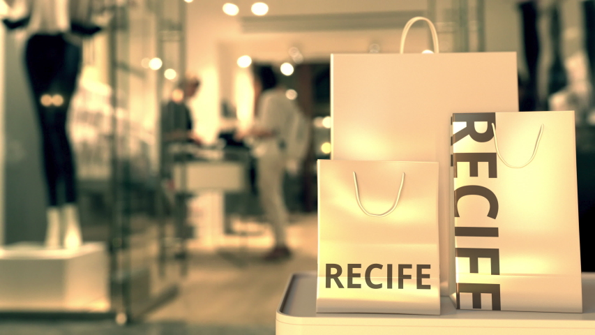 Paper shopping bags with Recife caption against blurred store entrance. Retail in Brazil related conceptual 3D animation