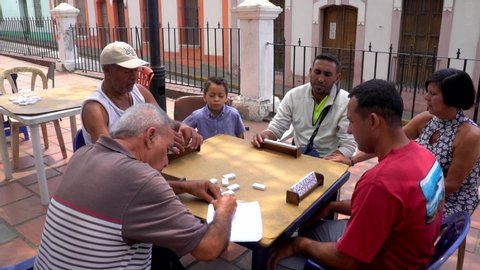 Unidentified people playing domino at the Antonio Jose de Sucre square in the colonial part of Petare district in Caracas, the capital of Venezuela, circa Mach 2019