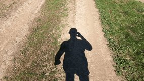 Shadow of a man walking along a country road