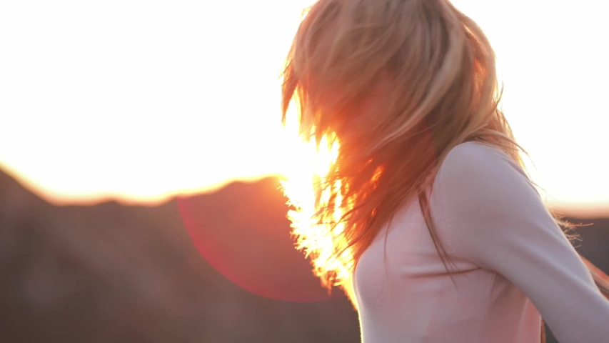 Back view of Young attractive girl young women traveler-blogger walk in mountain in plaid in sunshine flares sunset. Dressed in white clothes and a plaid. Red rocks