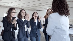 Cheerful businesswomen applauding and hugging. Group of happy multiethnic female colleagues celebrating success in office. Business success concept