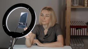 Female shoots video with a smartphone, illuminating the face of the led ring