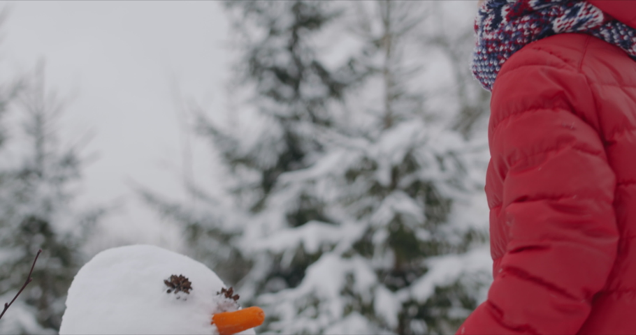 Cute little Caucasian kid putting a hat on a snowman, boy playing outside in winter. 4K UHD RAW Graded footage Royalty-Free Stock Footage #1044291718