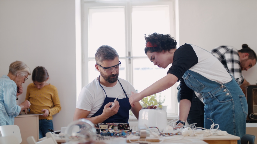 A group of people at repair cafe repairing household electrical devices. | Shutterstock HD Video #1044293296