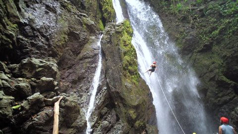 Canyoning In Costa Rica Waterfall - Rappelling down a large waterfall in central america