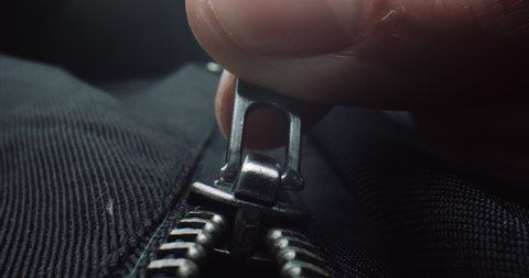 Close up of fingers zipping up a black jacket. Shot in 4K RAW on a cinema camera.